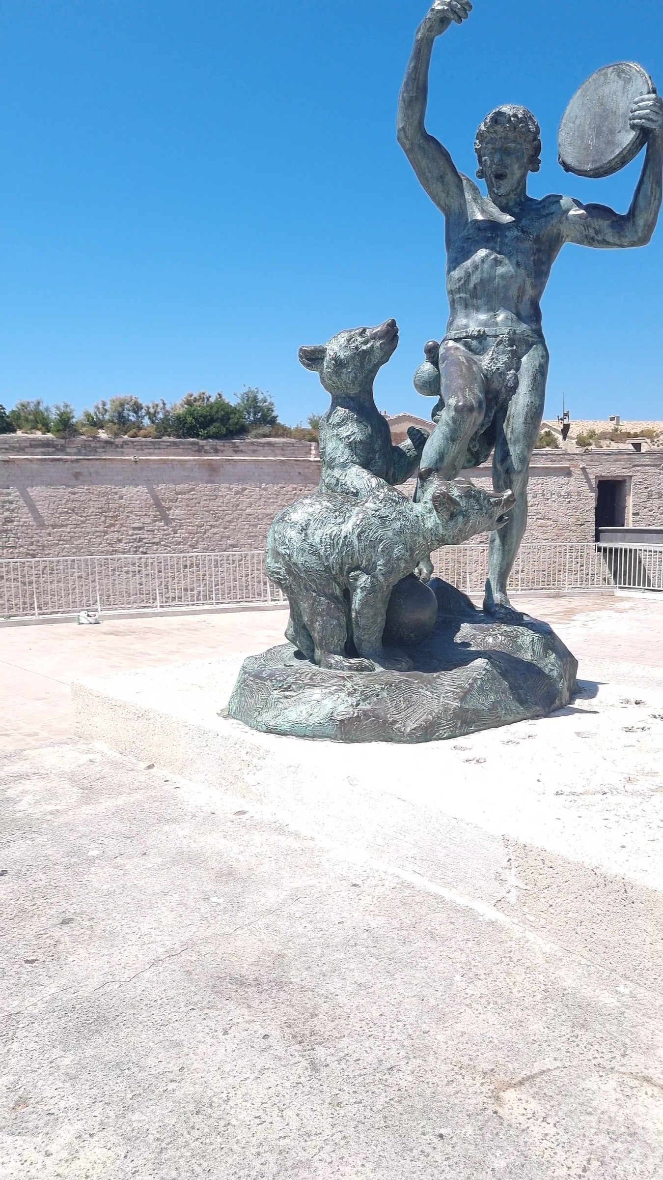 The same bronze statue from a closer position, with the tambourine raised against the sky.